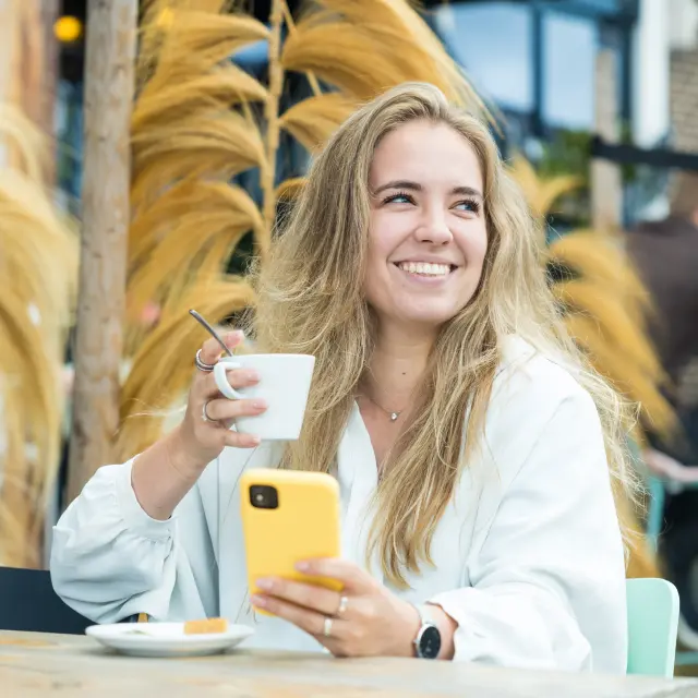 Telefoon in de hand en kopkoffie