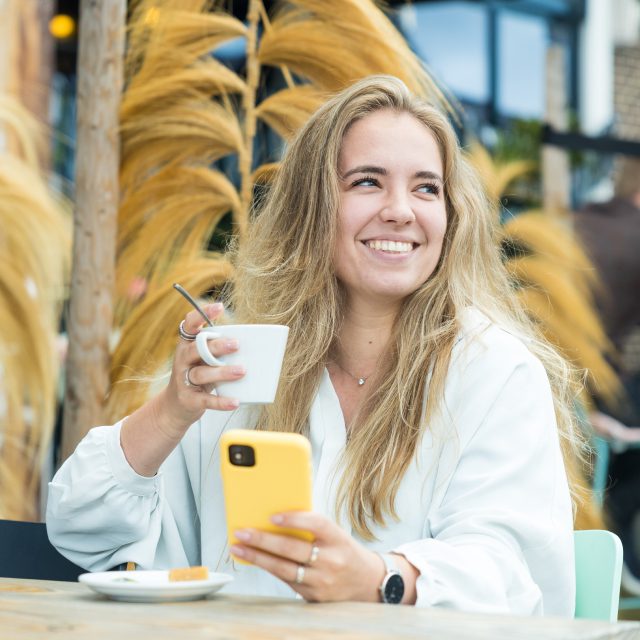 Telefoon in de hand en kopkoffie